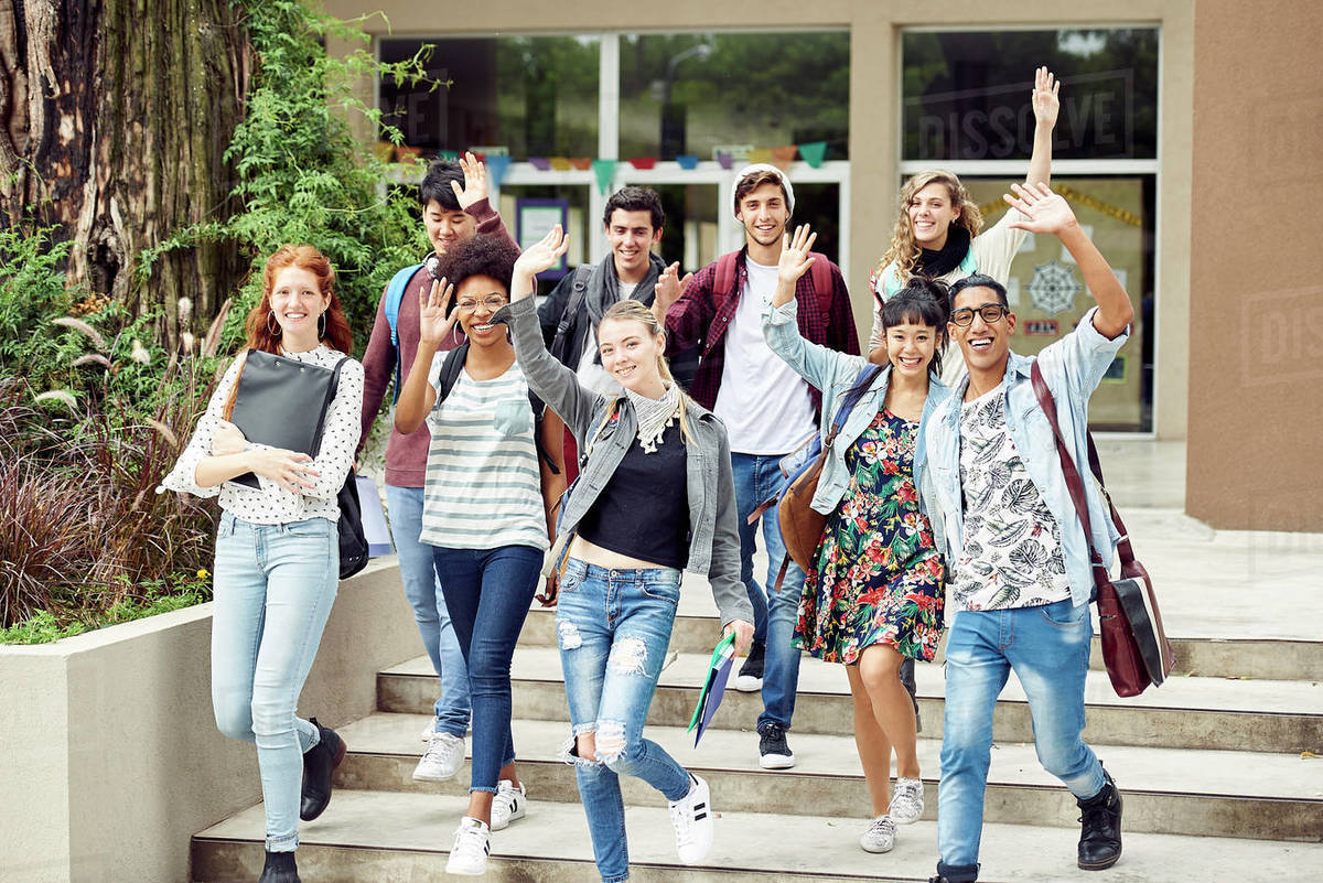 College students waving while walking on campus - Stock Photo - Dissolve